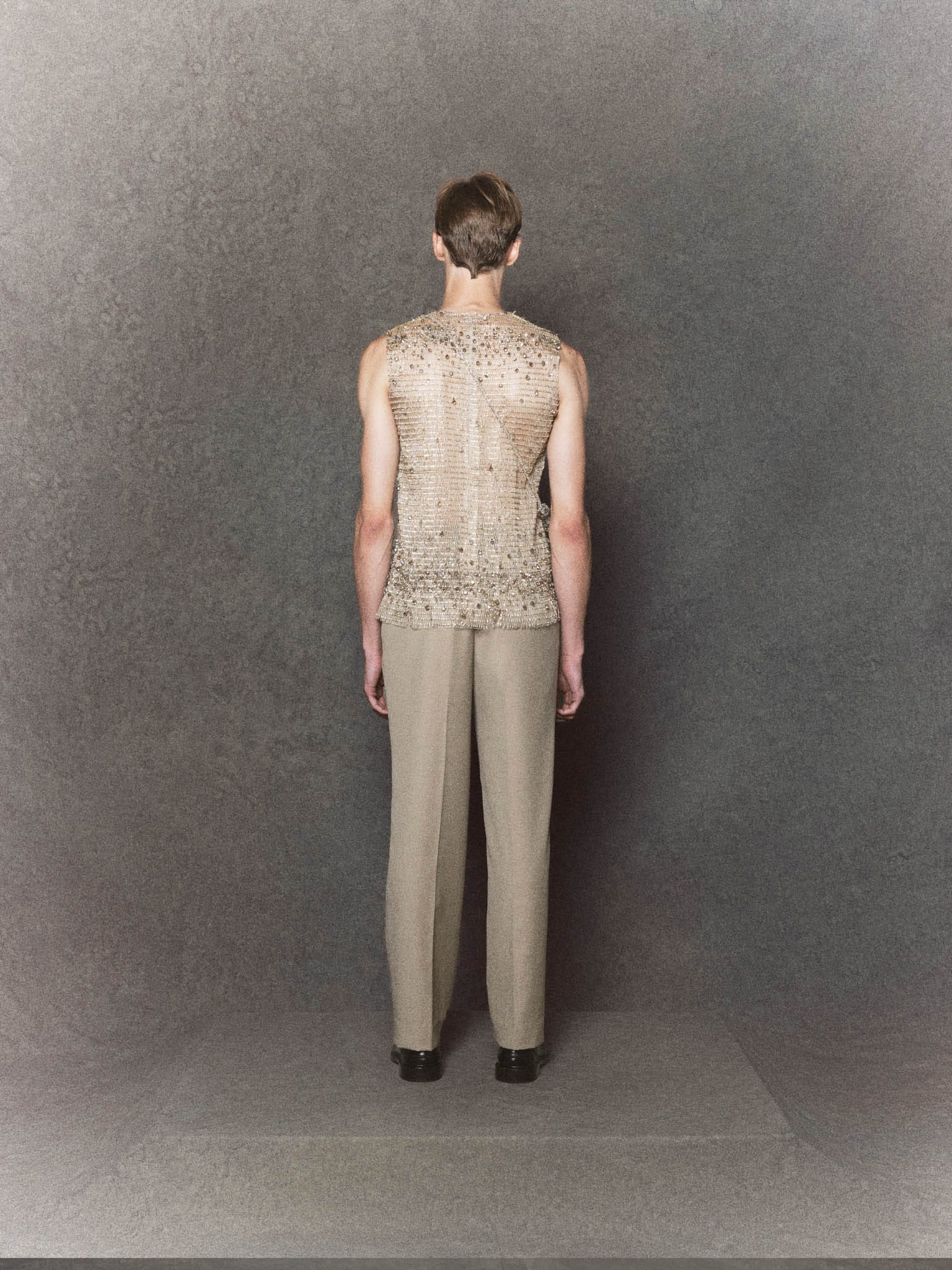 Nude mesh sleeveless top with crystal embellishments paired with gray trousers - Image 2