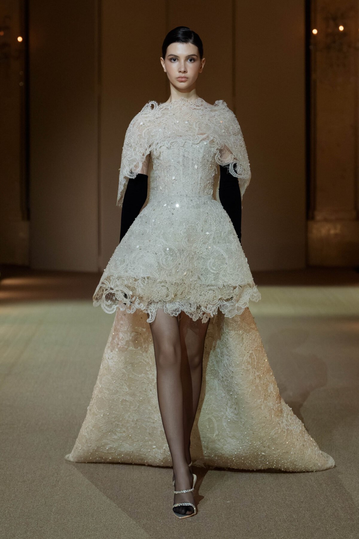 Creamy white guipure lace evening ensemble with a high-low shoulder cape