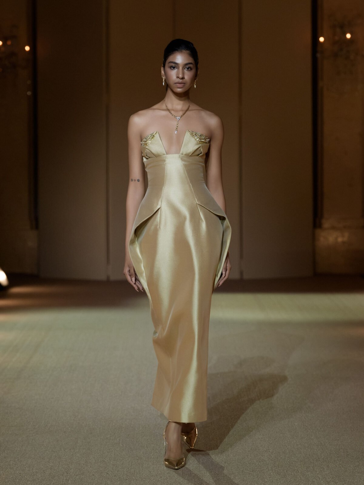 Beige strapless column dress with gold chain embellishment on the bust