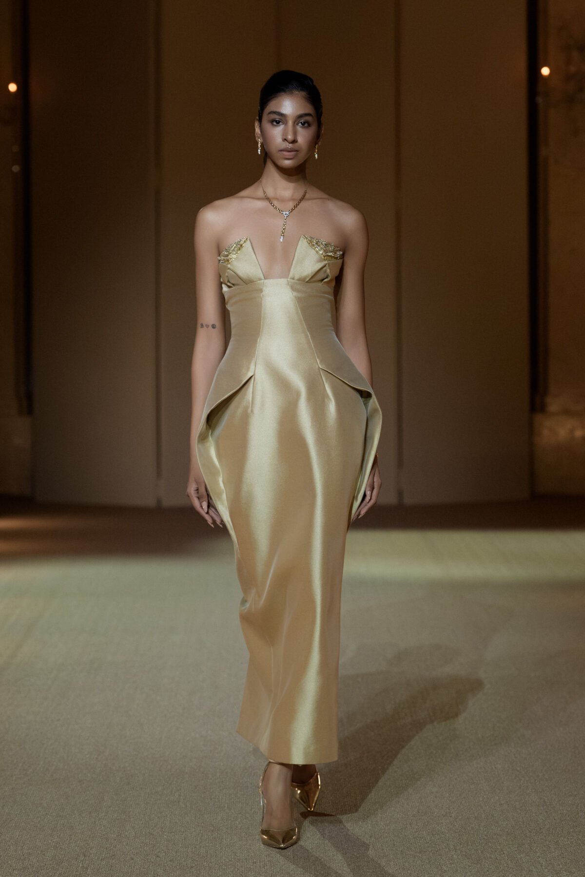 Beige strapless column dress with gold chain embellishment on the bust