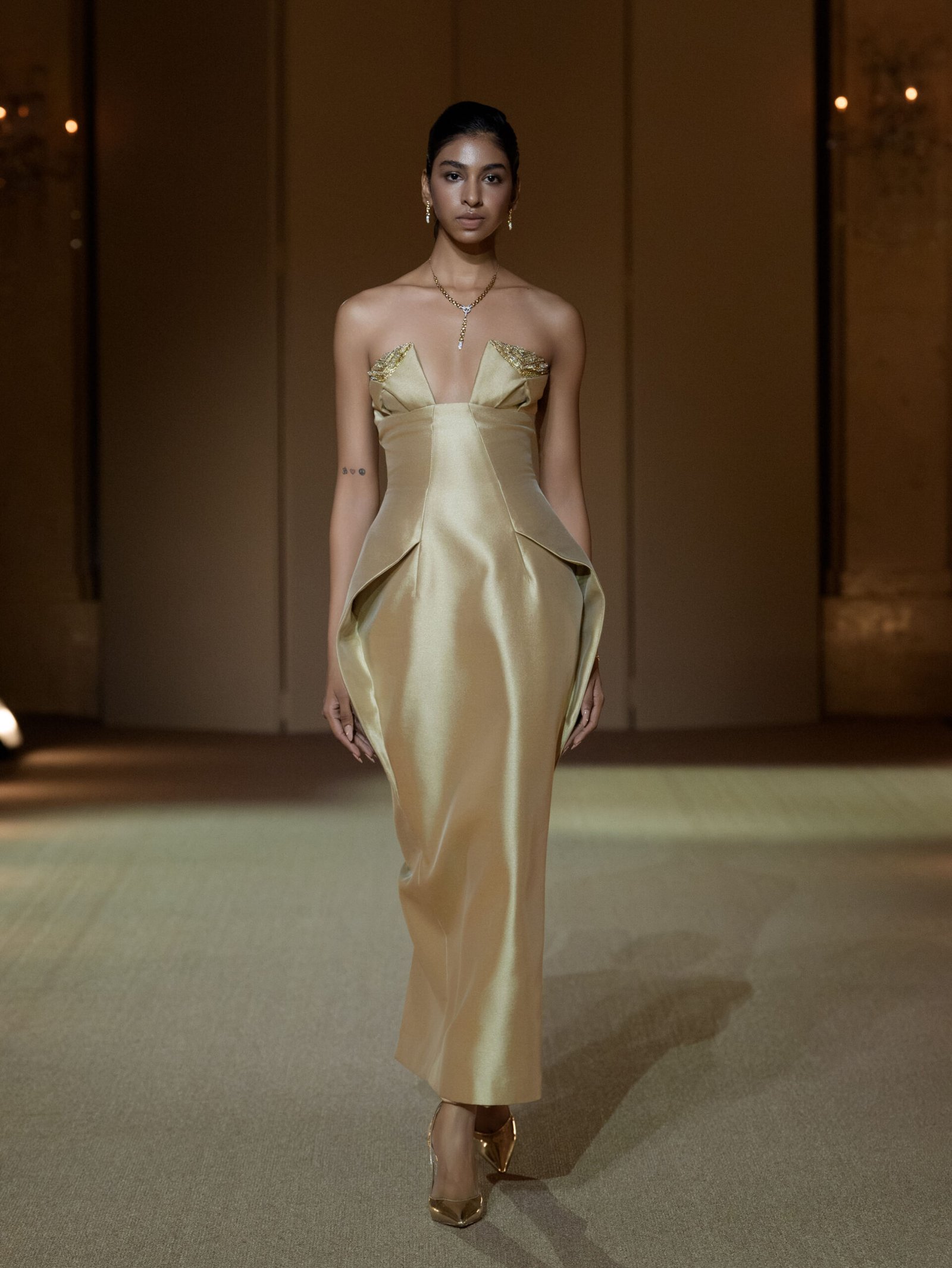 Beige strapless column dress with gold chain embellishment on the bust
