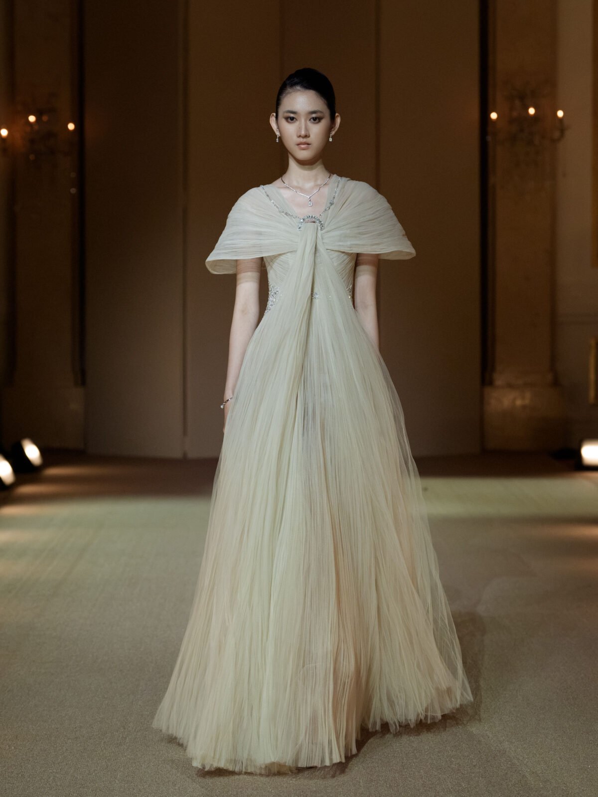 Beige hand-pleated tulle gown with cape sleeves and beaded embellishment