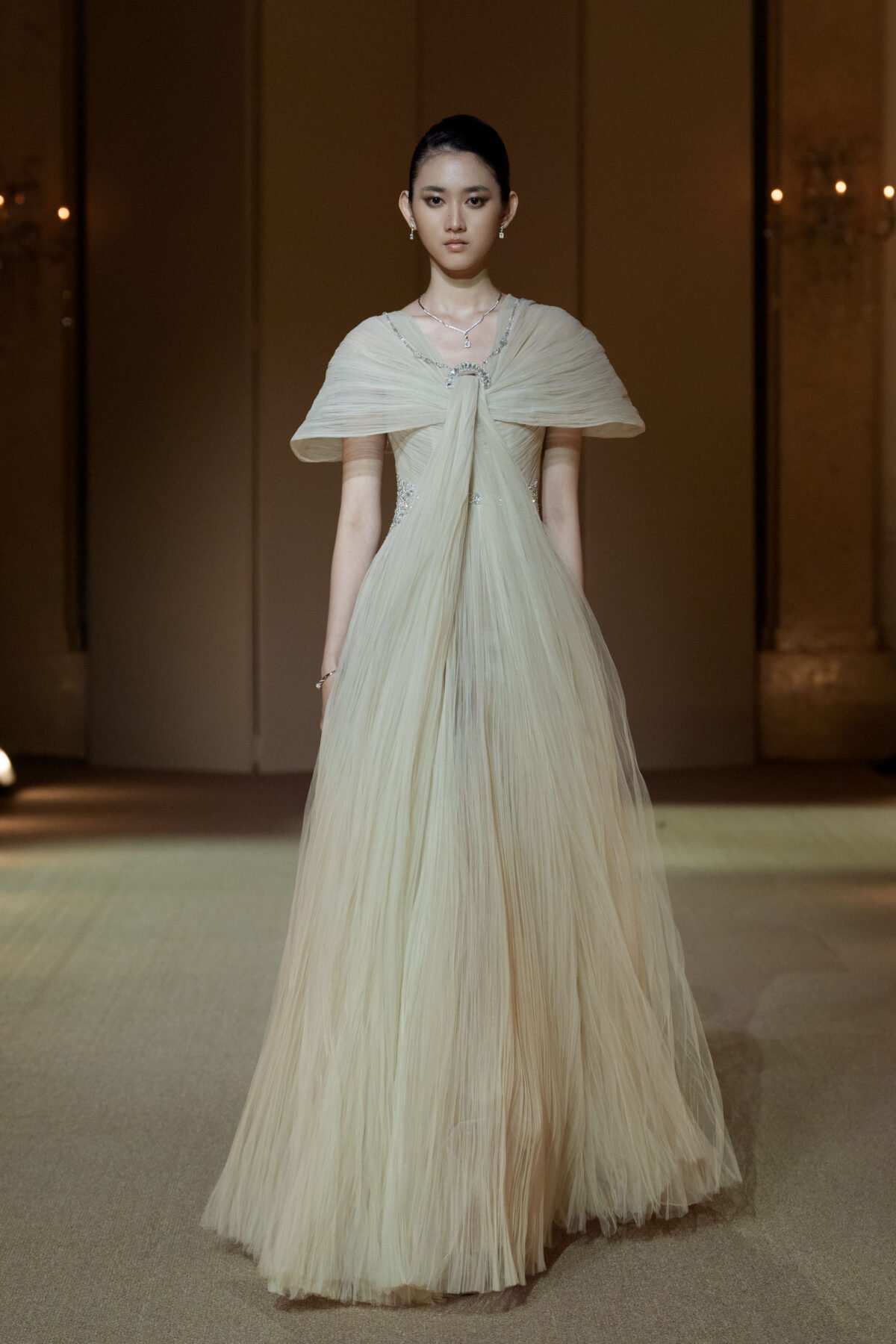 Beige hand-pleated tulle gown with cape sleeves and beaded embellishment
